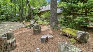 A forested area with a house, surrounded by trees and rocks. - Rustic Elegance. Three Fireplaces. A Crown Jewel of a Screened Porch | Sagee Woods (Highlands)