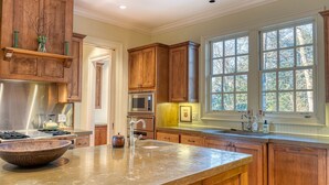 A kitchen with wooden cabinets, a stainless steel range, a large window with multiple panes, and a bowl on the counter. - Rustic Elegance. Three Fireplaces. A Crown Jewel of a Screened Porch | Sagee Woods (Highlands)