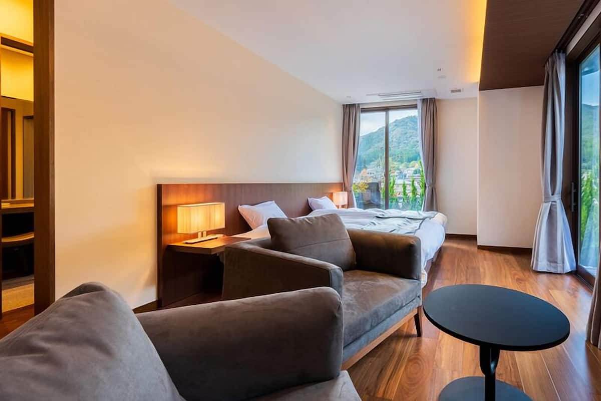 Una habitación de hotel con cama, sofá, una mesita y una mesita de noche con lámpara.