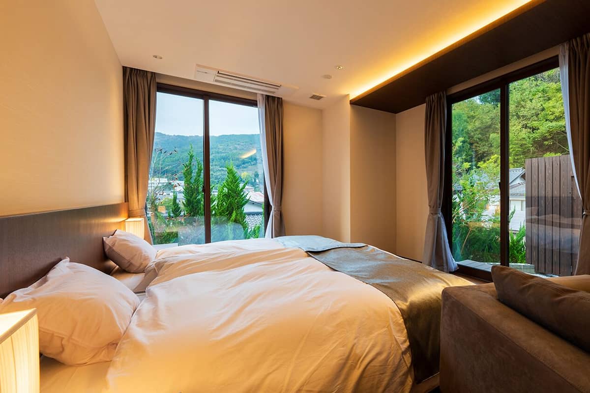 Habitación de hotel con una cama grande, un sofá, una ventana con cortinas y un equipo de aire acondicionado.
