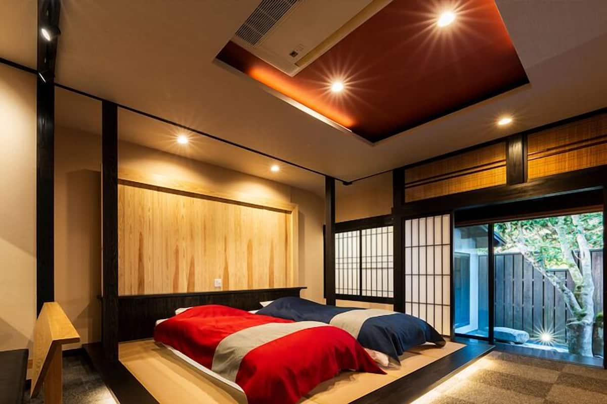 Un dormitorio moderno con una cama grande, panel de pared de madera, puertas correderas y una lámpara de techo.
