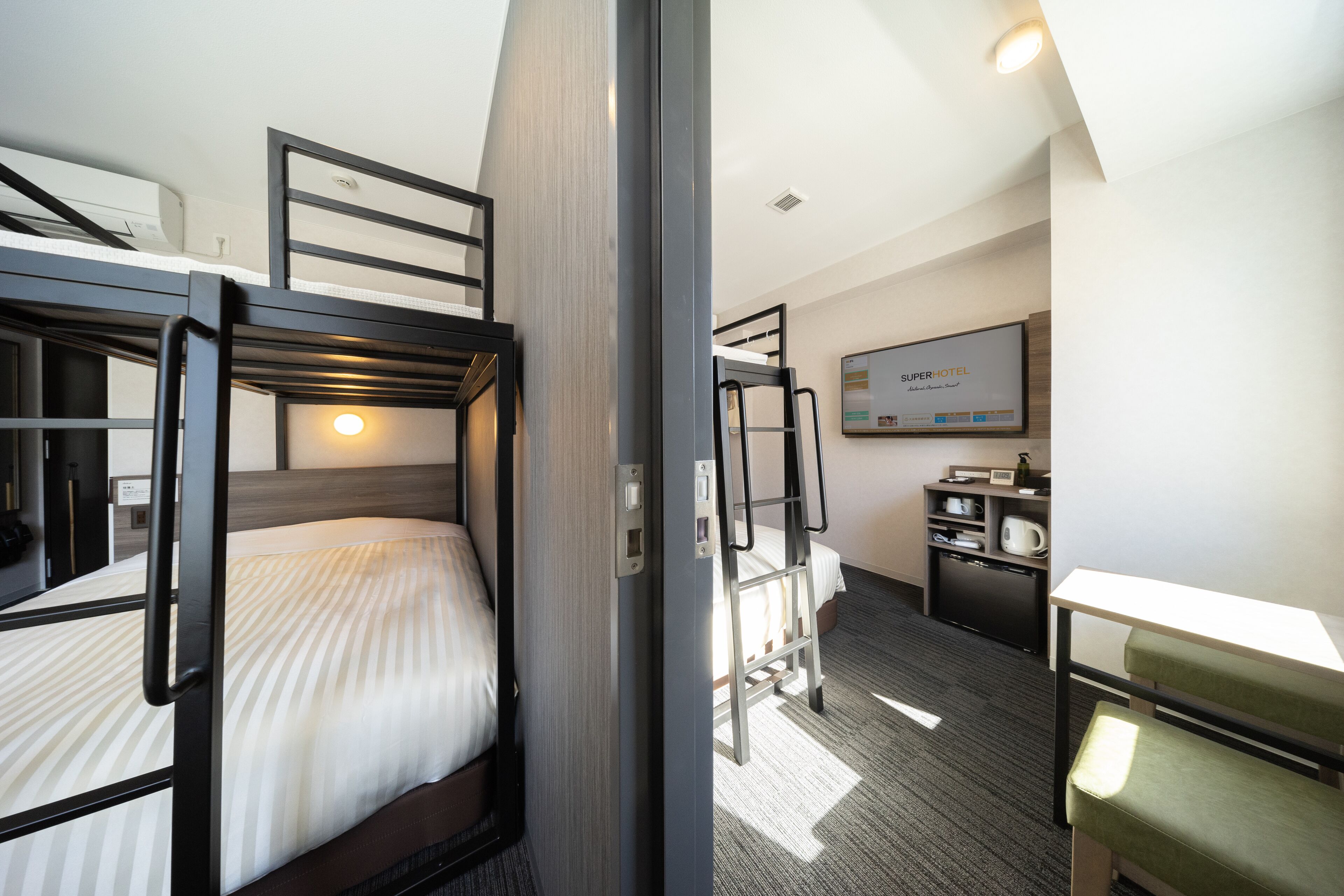 A hotel room with bunk beds, a desk, and a television.