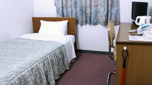 Een hotelkamer met een bed, een bureau met een computermonitor, een telefoon en een stoel.
