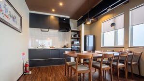A modern kitchen with wooden flooring, a dining area with wooden chairs, and a large window providing natural light. - Iroha Nozawa (Nozawaonsen)