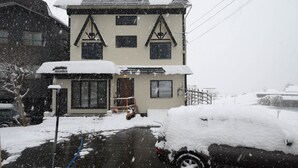 A two-story building with a snow-covered roof and windows. - Iroha Nozawa (Nozawaonsen)