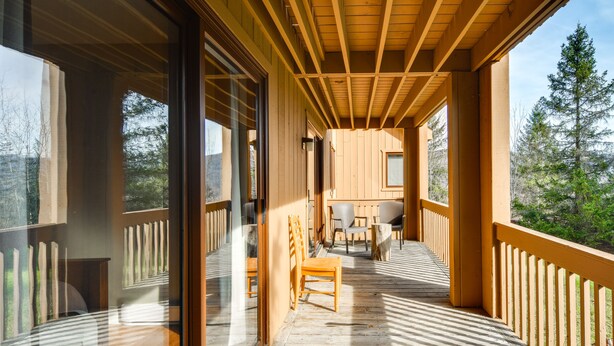 Eine Holzterrasse mit Geländer, einem Tisch und Stühlen.
