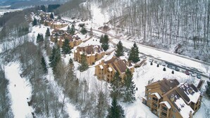 Ein schneebedecktes Resort mit mehreren Gebäuden, einer Seilbahn und einer Straße.