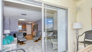 Een woonkamer met een bank, fauteuils en een glazen deur naar een balkon.