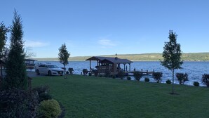 Une propriété située au bord d’un lac, avec un belvédère, une voiture garée et une pelouse verdoyante.