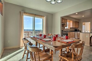 A spacious dining area with a long table set for six, wooden chairs, and a view through large windows.