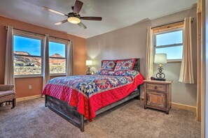 Ein Schlafzimmer mit einem Bett, einem Nachttisch, einem Sessel und einem Deckenventilator.