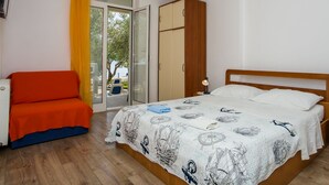 A bedroom with a bed, a chair, a wardrobe, and a window with curtains. - Apartments Glavor (Janjina)