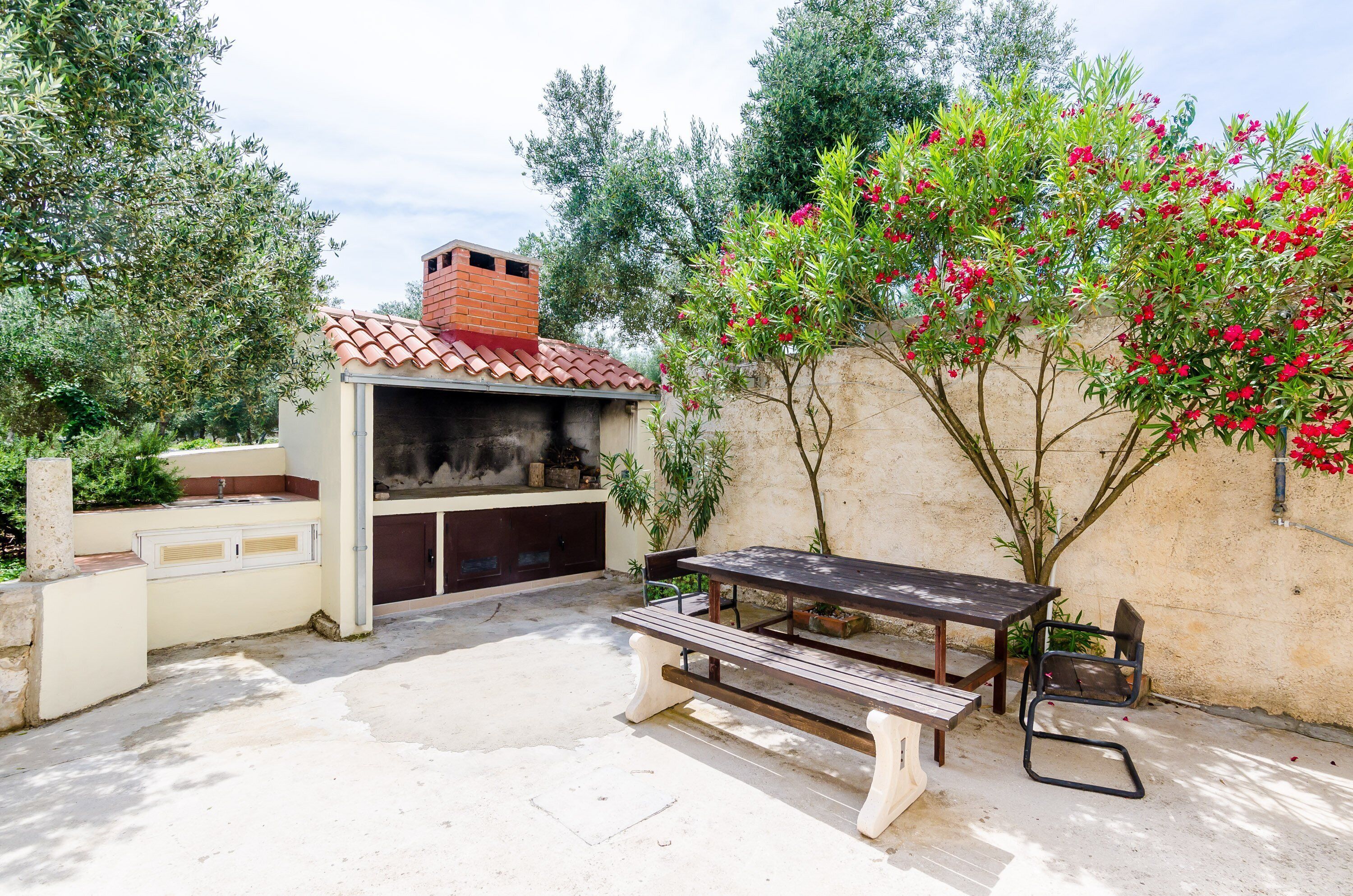 An outdoor patio with a barbecue grill, a table, and chairs.