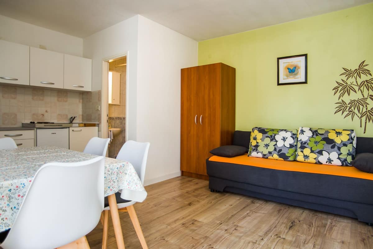 Un espacio habitable compacto con comedor, kitchenette y un sofá con cojines estampados.