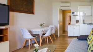 A compact living space with a dining area, kitchenette, and a TV mounted on the wall. - Apartments Glavor (Janjina)