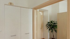 A hallway with a wooden floor, a potted plant, and a white wardrobe. - Apartment Mihe (Dubrovnik)