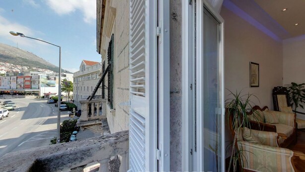 A hotel room with a balcony overlooking a street and a hill. - Apartment Mihe (Dubrovnik)