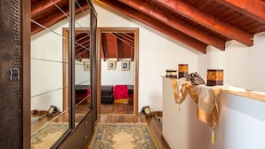 A room with a wooden ceiling, a bed with a red blanket, a small table with decorative items, and a mirror reflecting the room. - Villa Marilia - Lux home near Beach (Rhodes)
