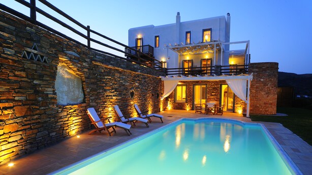 Ein modernes Haus mit Swimmingpool, Steinmauern und Sitzgelegenheiten im Freien.
