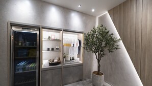 Ein modernes Interieur mit einer gekühlten Verkaufstheke, Regalen mit Artikeln und einem Blumentopf.