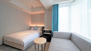 A hotel room with a bed, a sofa, a small table, a nightstand, and a window with curtains. - Hotel Oriental Express Fukuoka Tenjin (Fukuoka)