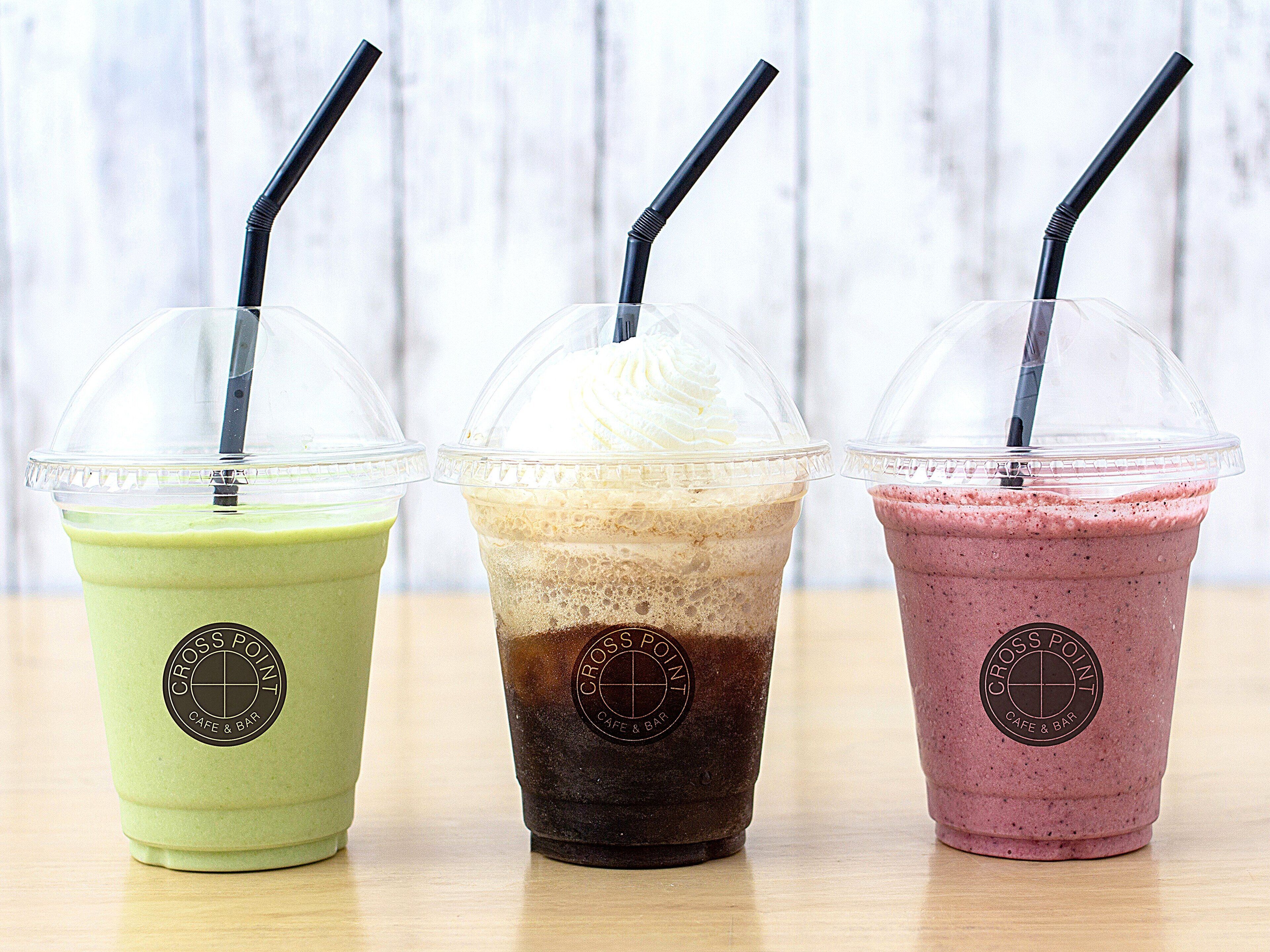 Three iced drinks in clear plastic cups with black straws, each labeled with a logo.