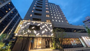 Ein modernes Hotel mit einer geometrischen Fassade, großen Fenstern und einem gut beleuchteten Eingang.