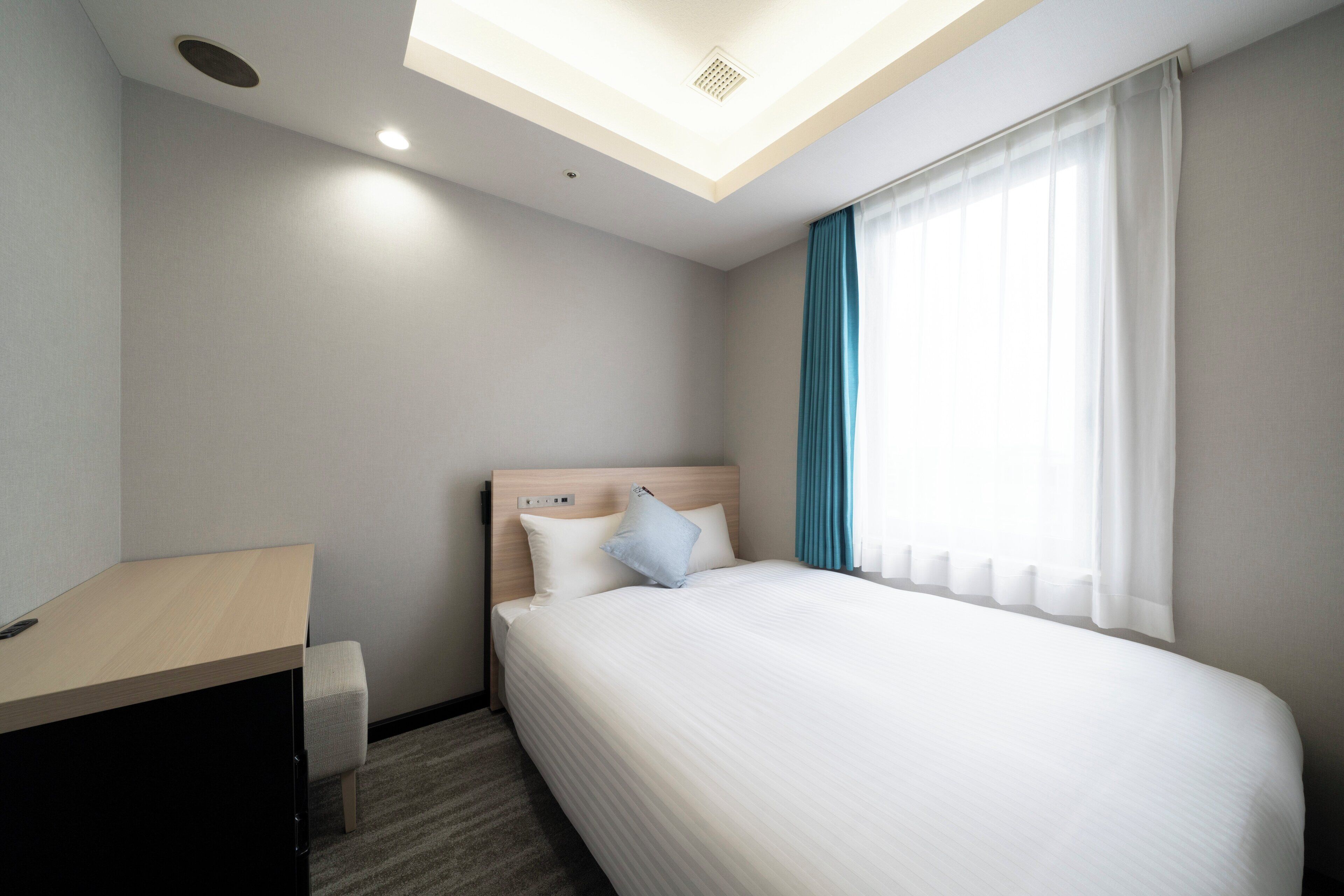 Una habitación de hotel moderna con una cama, un escritorio y un tragaluz.