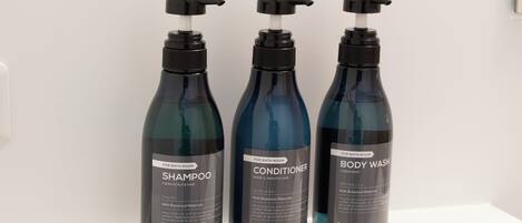 Three bottles of bathroom products on a shelf.