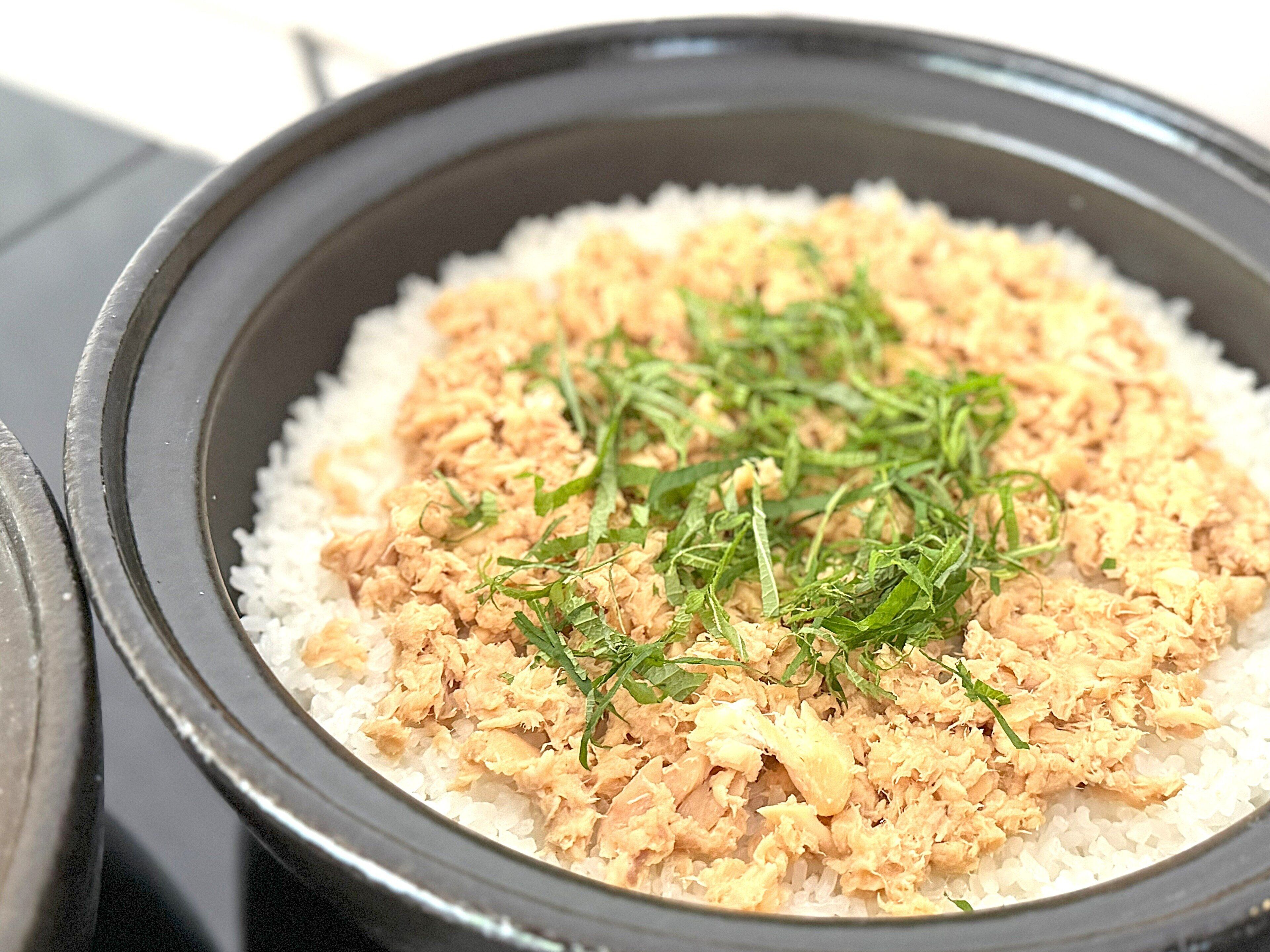 A dish with shredded chicken and rice in a black bowl.