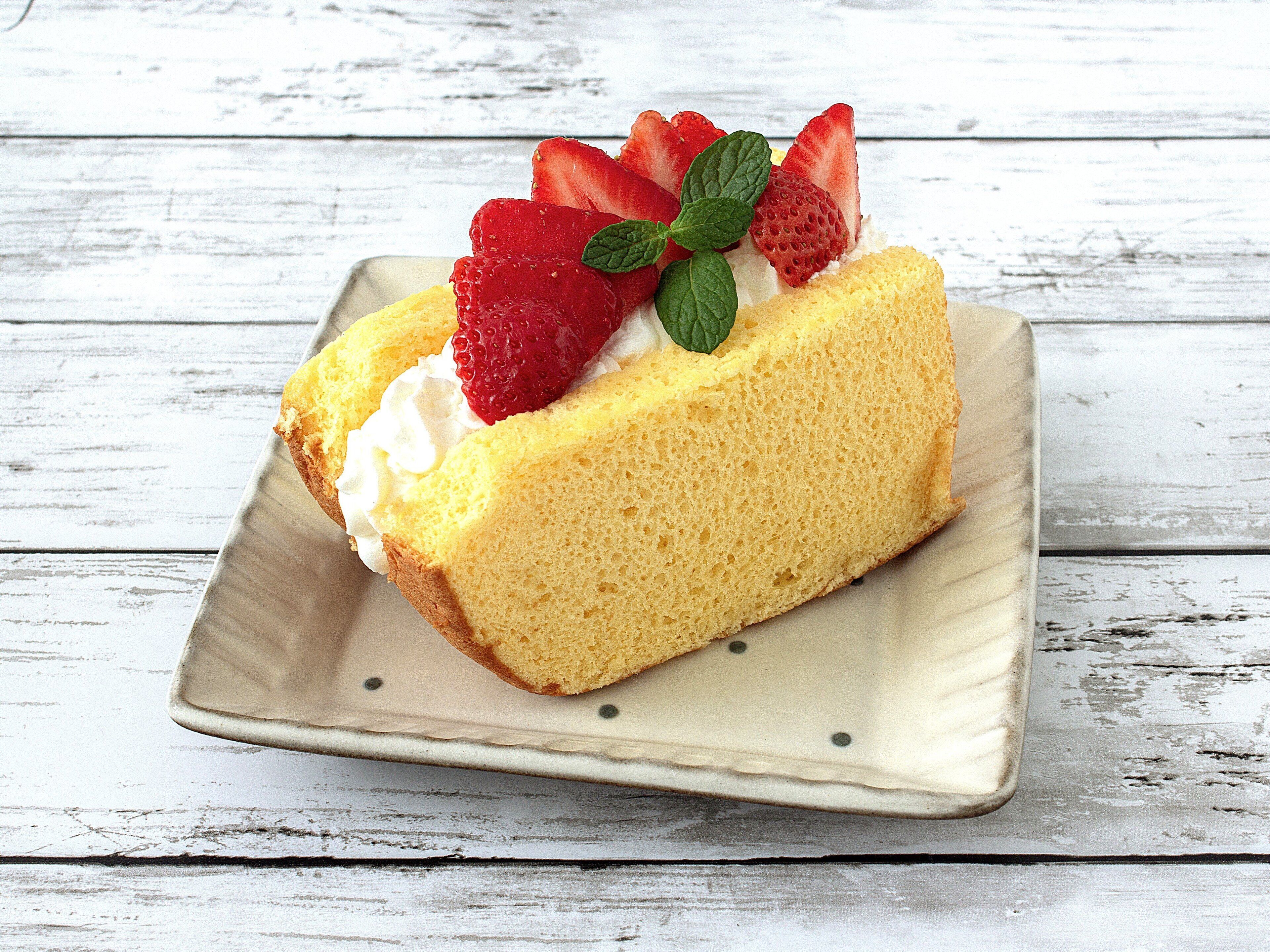 Una rebanada de pastel con fresas y menta en un plato.