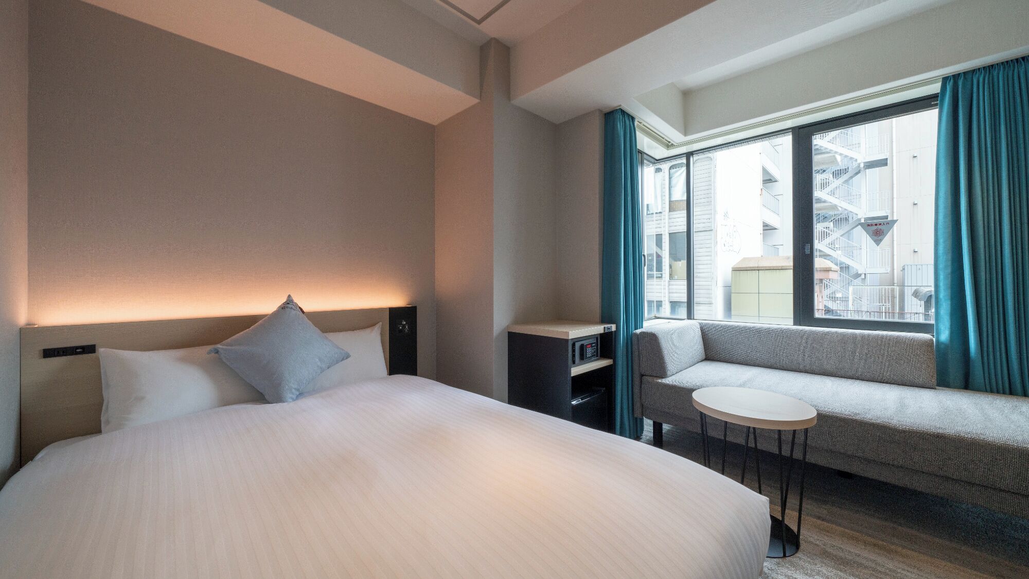 Une chambre d’hôtel avec un grand lit, un canapé, une petite table et une fenêtre avec des rideaux.