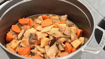 A pot containing a stew with chunks of meat and vegetables.