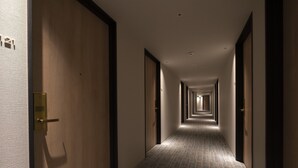 Ein Hotelgang mit Holztüren, Teppichboden und einer Reihe von Leuchten an der Decke.
