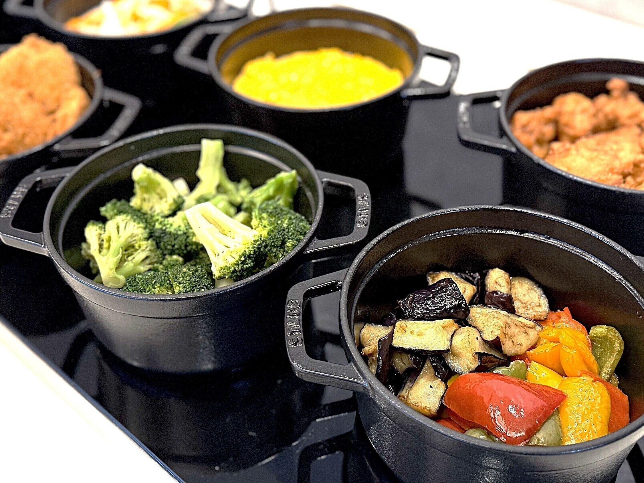 Um fogão com várias panelas cheias de legumes variados.