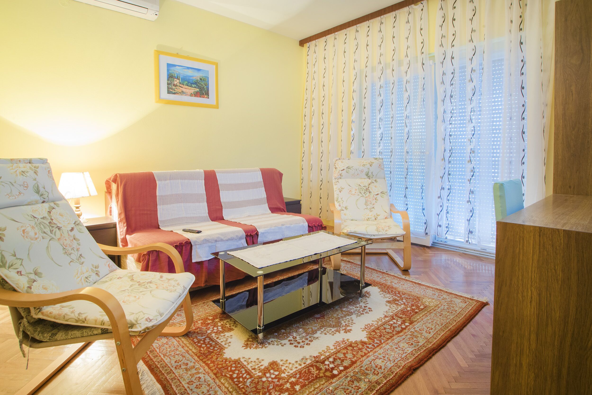 Een woonkamer met een bank, twee fauteuils, een bijzettafeltje en een kamerkleed met een patroon.