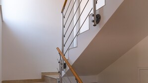A staircase with beige carpeted steps, a wooden handrail, and metal railings. - Apartment Relax Ston (Ston)