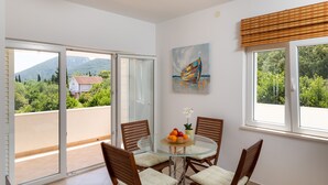 A balcony with a glass door, a round glass table with chairs, a painting, and a window with blinds. - Apartment Relax Ston (Ston)