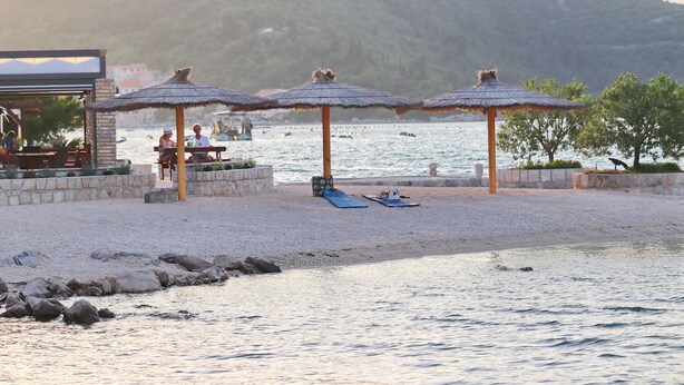 A beachside area with thatched umbrellas, a seating area, and a view of the sea. - Apartment Relax Ston (Ston)