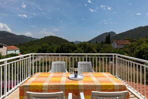 A balcony with a table set for two, overlooking a mountainous landscape. - Apartment Relax Ston (Ston)