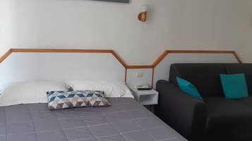 Una habitación de hotel con una cama, una mesita de noche, una lámpara y un sofá.