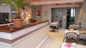 A modern hotel lobby with a reception desk, a dining area with tables and chairs, and a large potted plant. - Hotel de La Croix de Malte (Cherbourg-en-Cotentin)