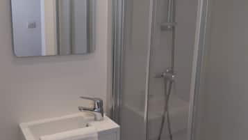A modern bathroom with a glass-enclosed shower, a white sink, and a mirror above the sink.
