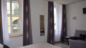 A hotel room with a bed, a sofa, a small table, and a mirror. - Hotel de La Croix de Malte (Cherbourg-en-Cotentin)