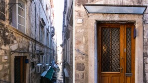 Un callejón estrecho con una puerta de madera y una ventana con reja de metal.