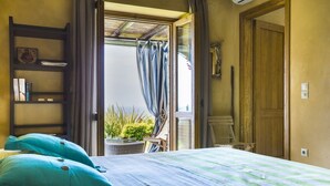 A bedroom with a bed, a wooden ladder, a shelf with books, and a view of a garden through an open door. - Villa Le Rondini - Two Bedroom Villa, Sleeps 4 (Ionian Islands)