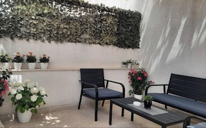 An outdoor seating area with two black chairs and a table, surrounded by potted plants and flowers. - Apartment Adea (Dubrovnik)