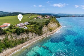 A coastal property with a view of the sea, a vineyard, and a hilly landscape. - Pool Apartments Debeli Rtič (Ankaran)