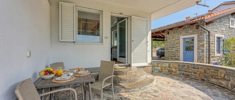 A patio with stone flooring, wicker furniture, and a table set for breakfast.