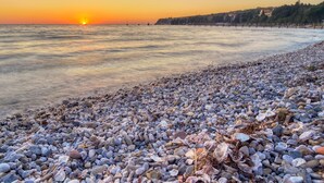 Una platja de petits còdols amb un cel ocre al fons.
